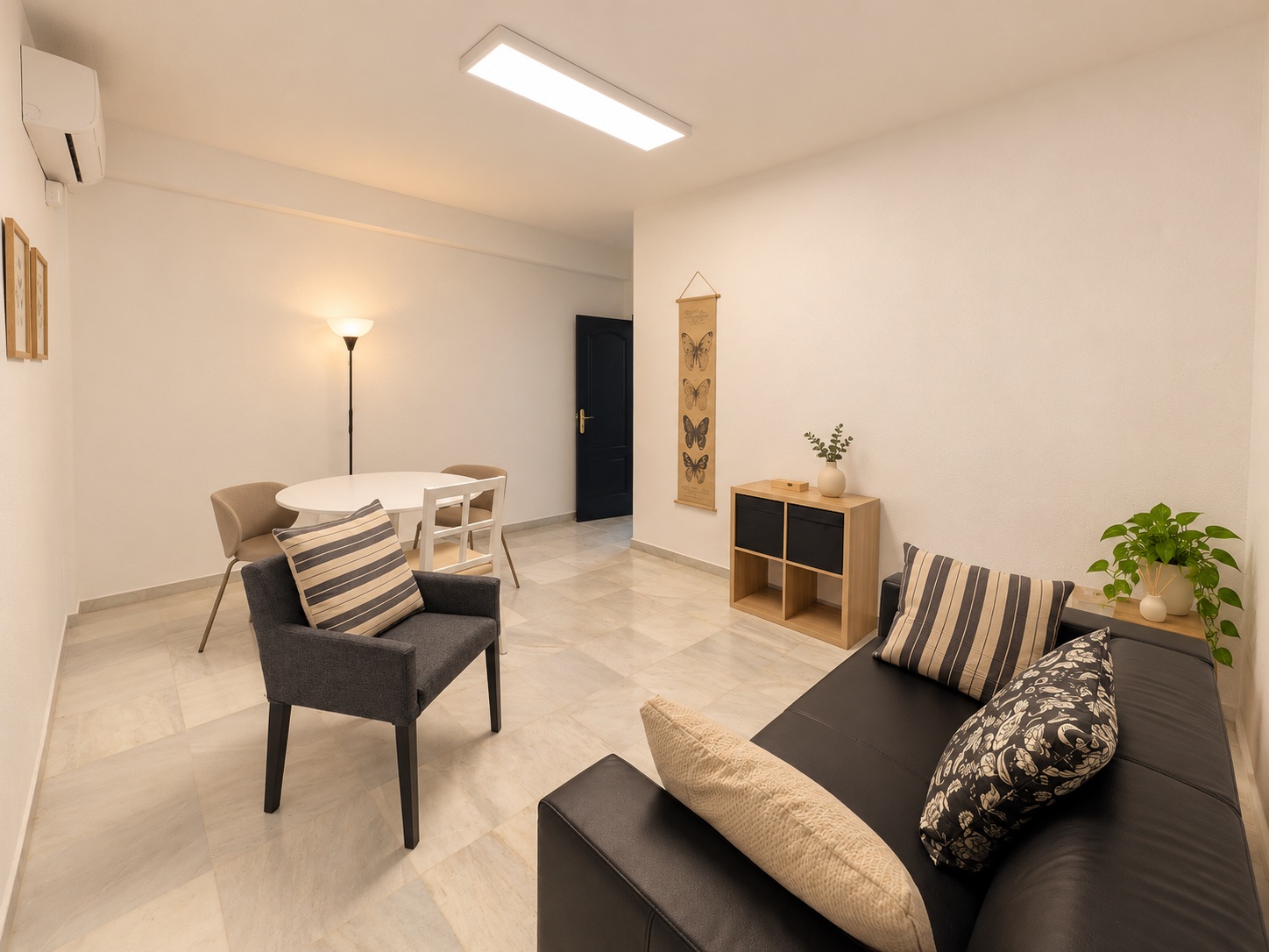 Sala con sofá, butaca y mesa al fondo